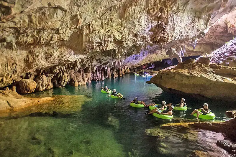 Glowing underground cave river with tubing adventurers in Belize